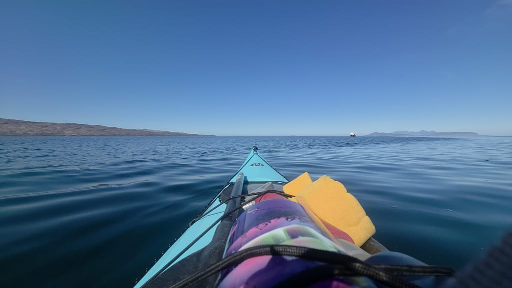Kayak ile açık denizde seyir halindeki bir manzara, su yüzeyi ve uzaktaki kıyı görünümü.