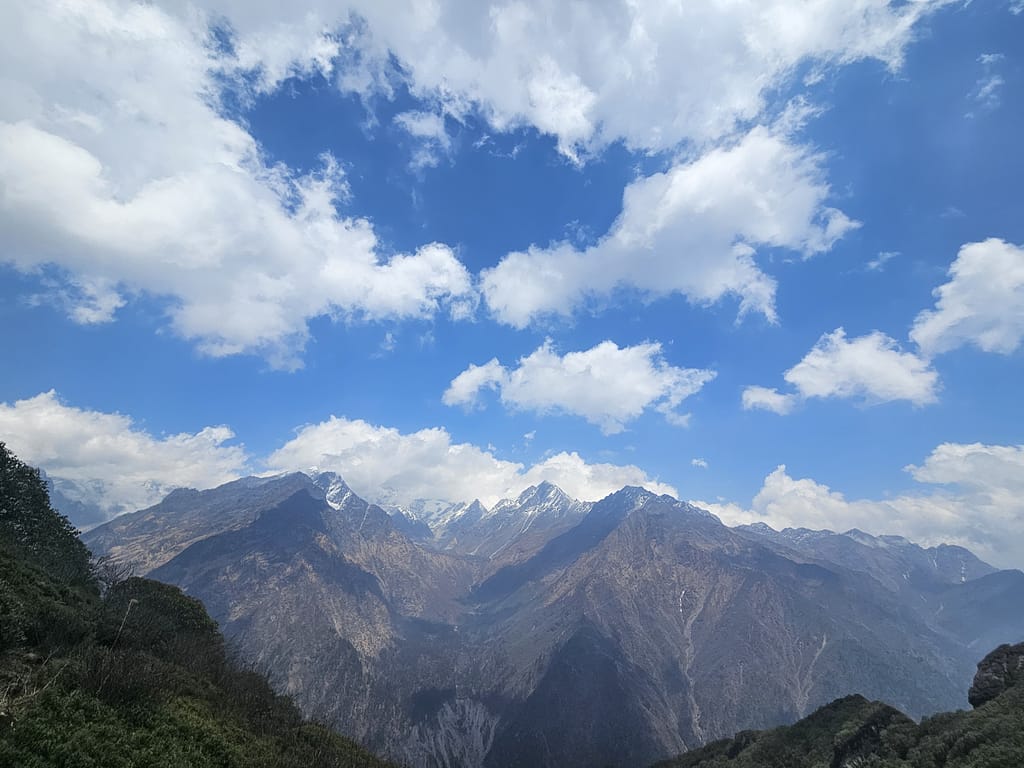 Himalaya dağlarının muhteşem manzarası, mavi gökyüzü ile beyaz bulutlar arasında uzanan zirveler.