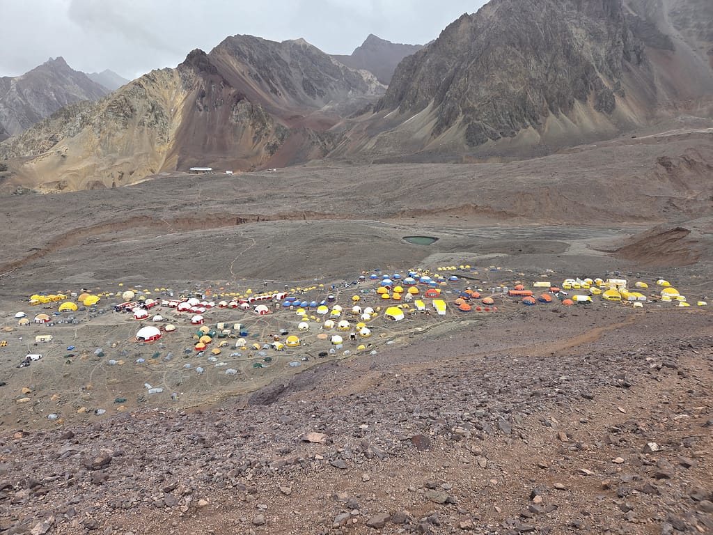 Dağlık bir bölgede yer alan renkli çadırlar ve kamp alanı manzarası.