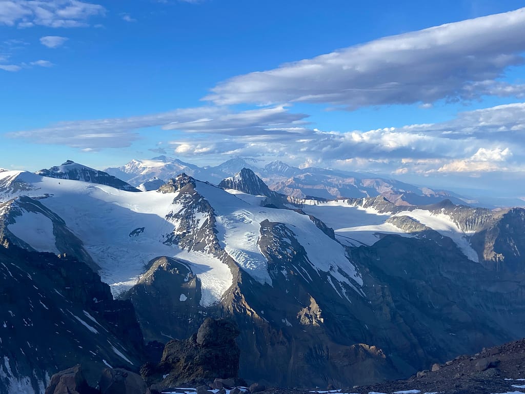 Karla kaplı dağ sıralarının ve açık mavi gökyüzünün görüntüsü.