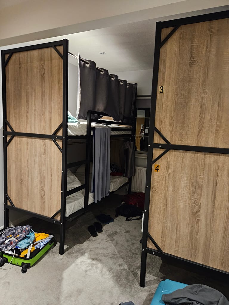 The bedroom has an open and closed bunk bed arrangement, with clothes and belongings on the floor.
