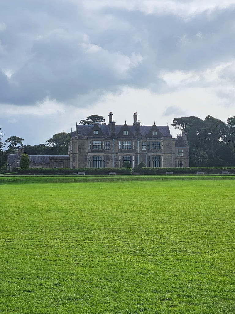 A large area of ​​green grass in front of Muckross Manor.