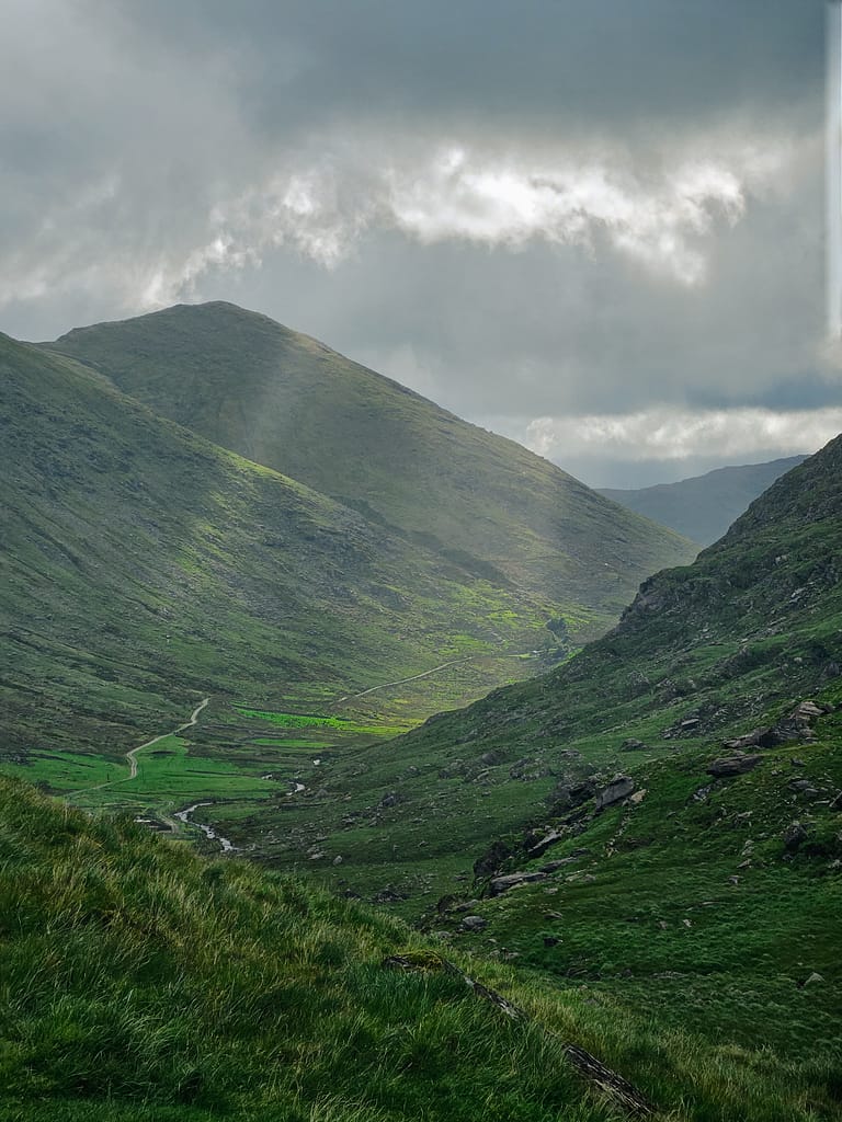 The entry shows a natural landscape of green valleys and mountains, with grey clouds overhead and beams of light in between.