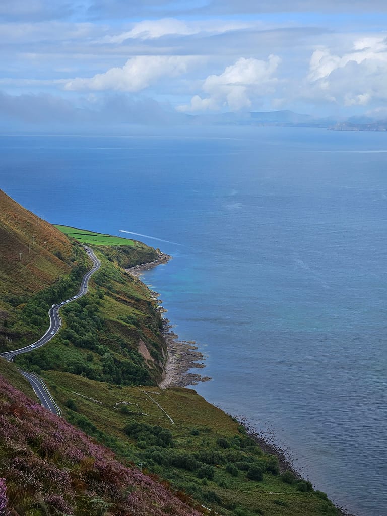 View of the lush green hillsides overlooking the sea and the winding Ring of Kerry road.