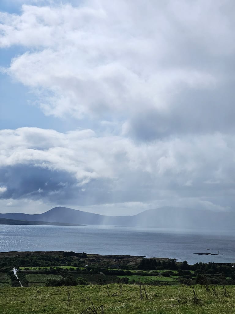 A natural landscape with a wide sea view in the foreground and clouds in the sky.