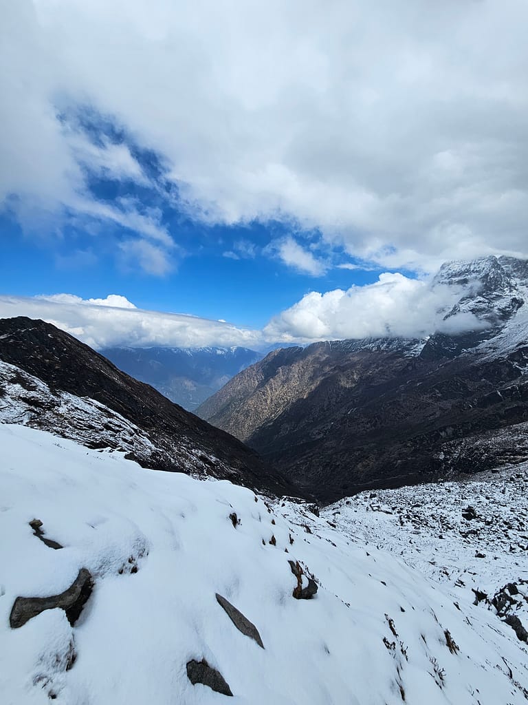 Karla kaplı dağ yamaçlarının ve açık mavi gökyüzünün göründüğü bir dağ manzarası.