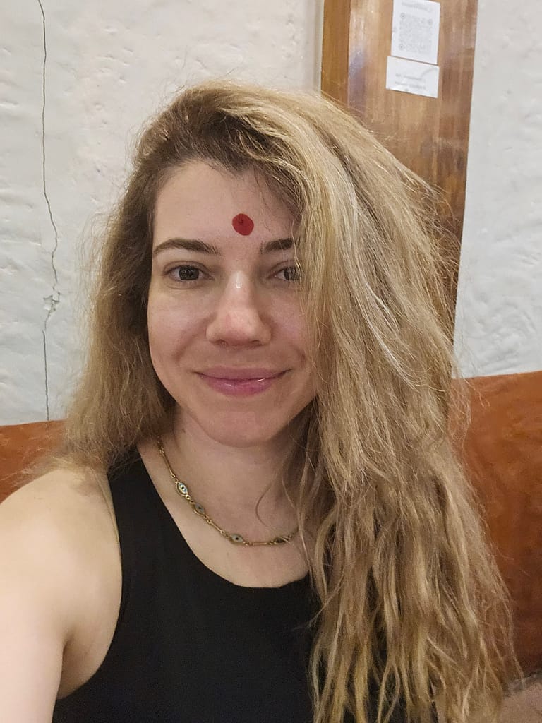 Gülen bir kadın, kahverengi duvarda ve doğal bir ortamda çekilmiş selfie'si.