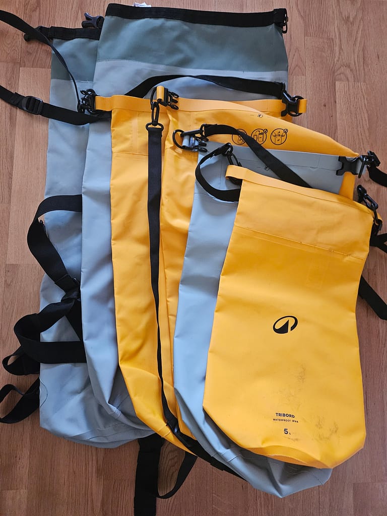 Waterproof dry bags of various sizes stand together vertically.