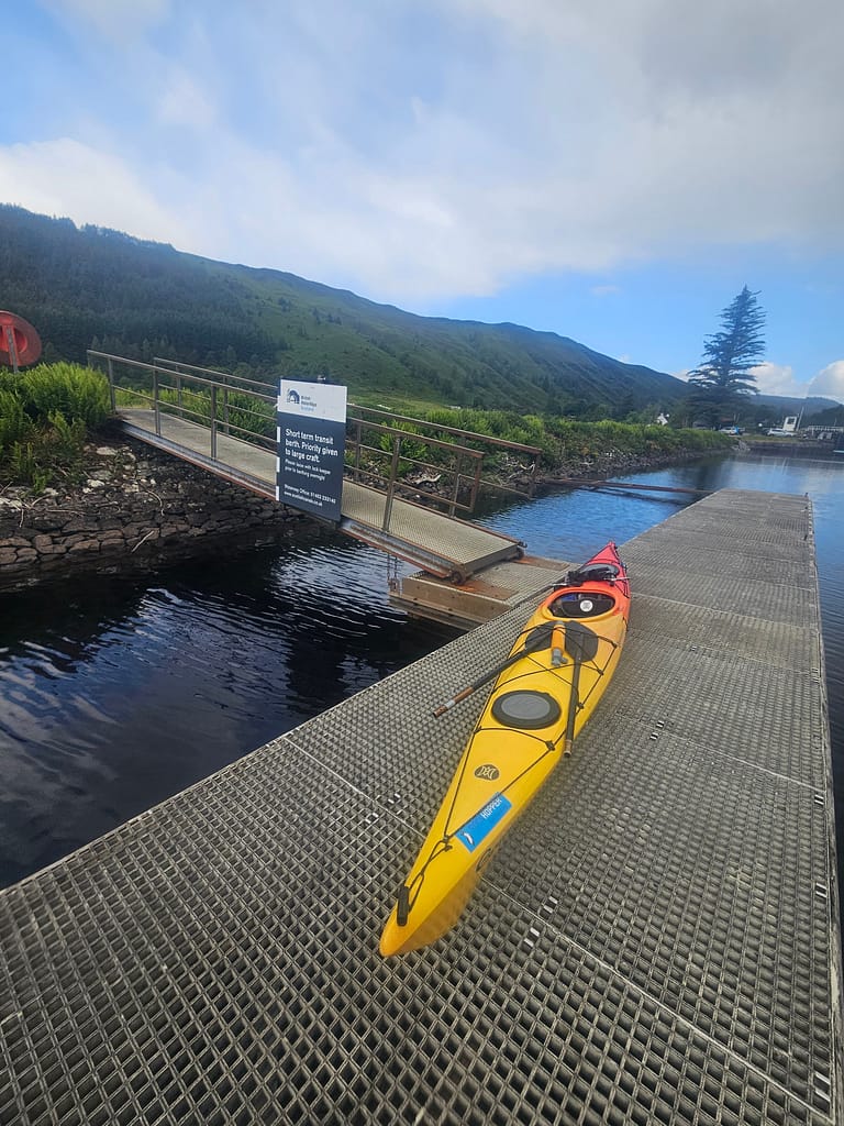 A landscape with a boat at a dock and green mountains and water around it.