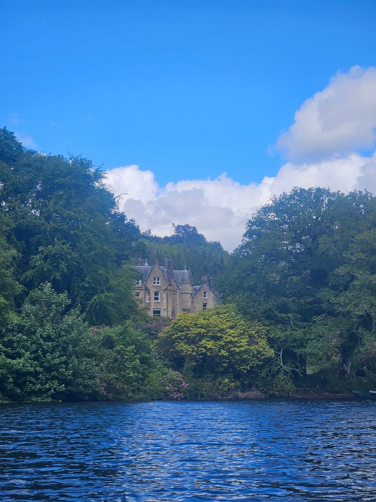 A historical building surrounded by lush trees overlooking the lake.