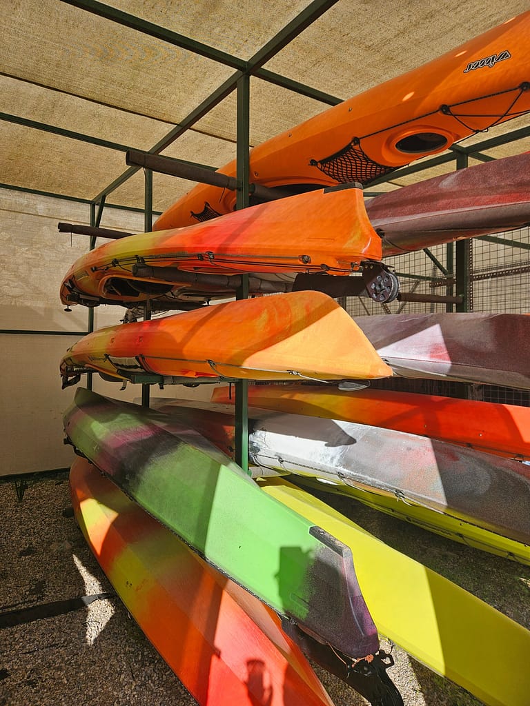 Raf üzerinde düzenli bir şekilde yerleştirilmiş, farklı renklerde deniz kayıkları.