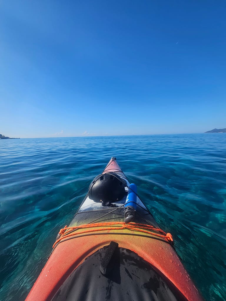 Bir deniz kayığı ile sakin bir deniz manzarası. Uzakta dağlık alanlar görünmekte.