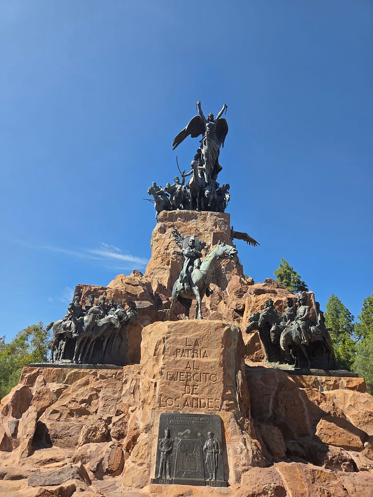 Andes Ordusu Anıtı, üstünde bir melek figürü ile birlikte asker heykelleri barındıran, mavi gökyüzü arka planda olan büyük bir anıt.