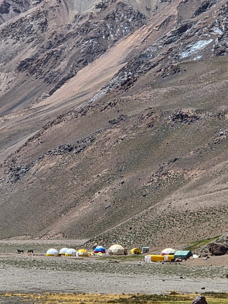 Dağlık alanda yer alan çeşitli renklerde çadırlardan oluşan bir kamp alanı.