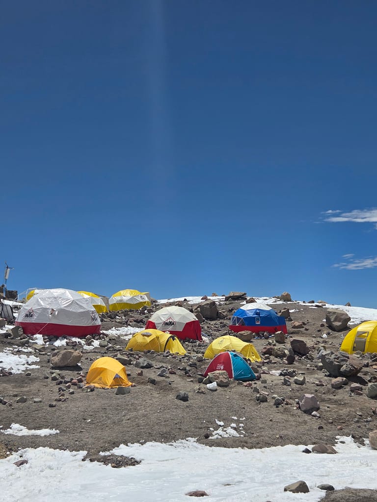 Yüksek bir dağlık alanda yer alan çeşitli renklerde çadırlardan oluşan bir görüntü.