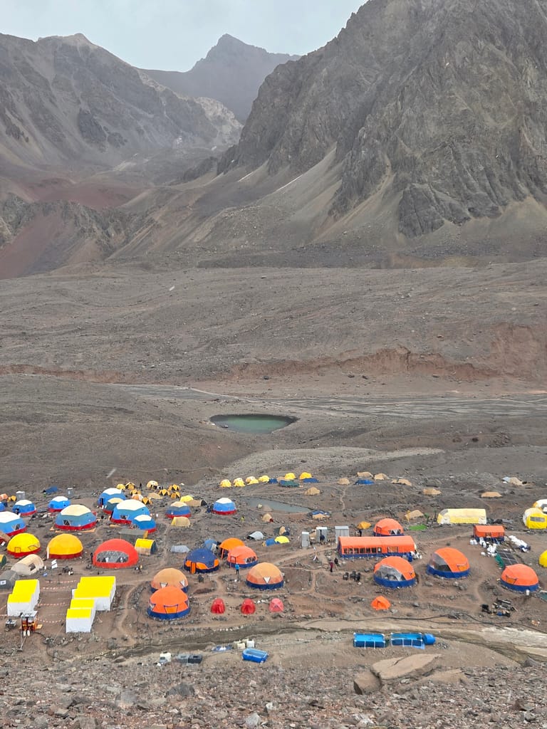 Dağlık alanda renkli çadırlarla dolu bir kamp alanı görünümü.